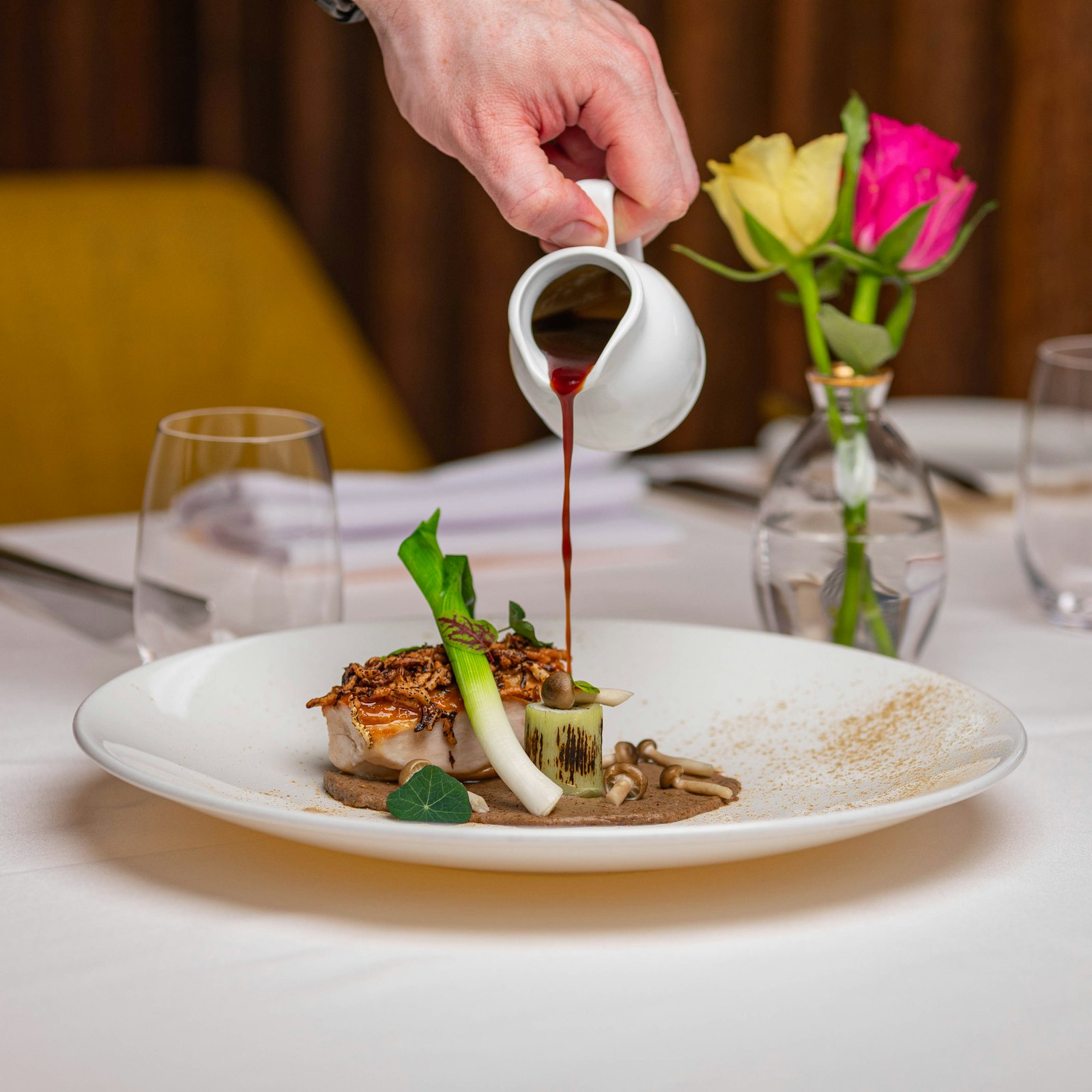 Chef's hands plating a refined dish in the kitchen